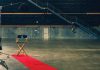 A directors chair at the end of a red carpet in an empty sound stage