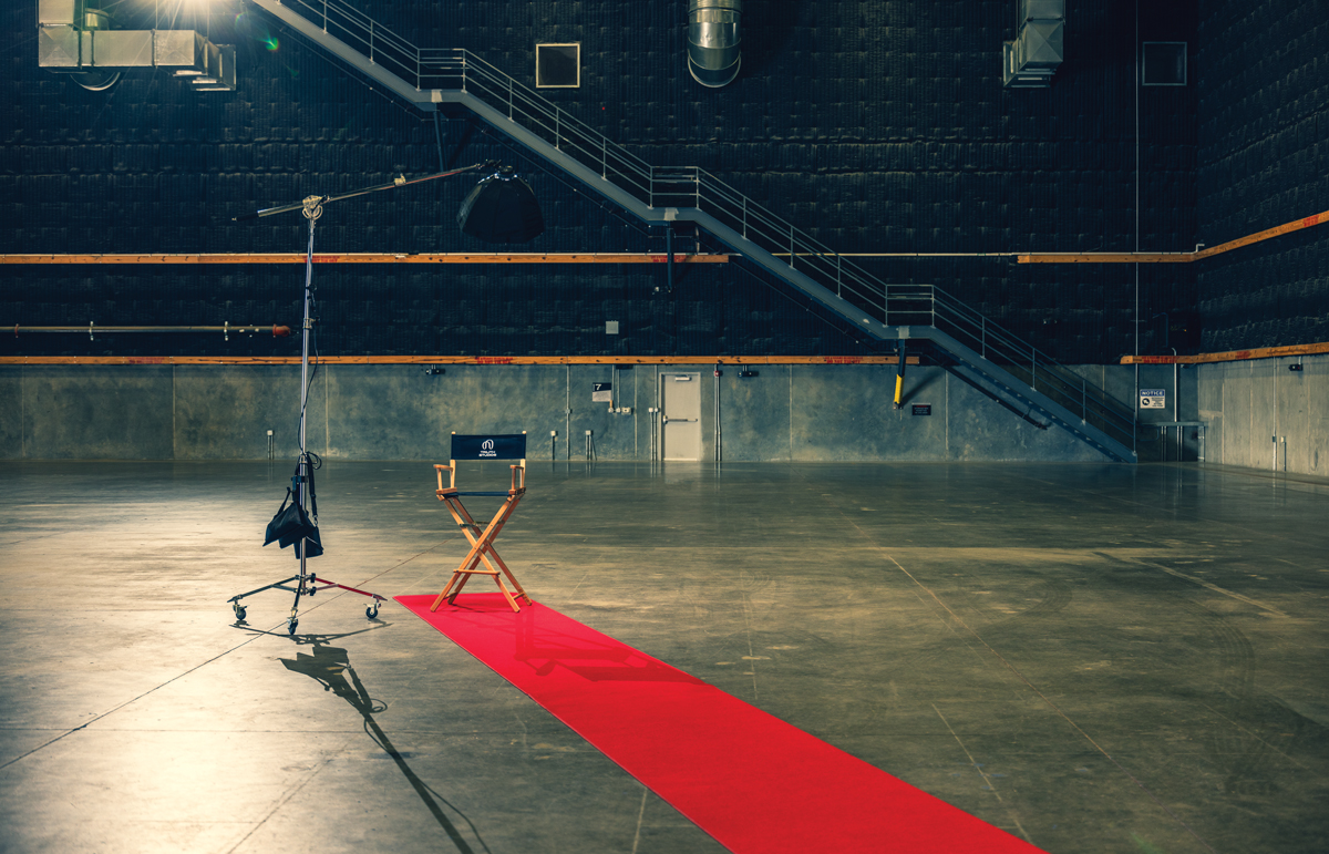 A directors chair at the end of a red carpet in an empty sound stage