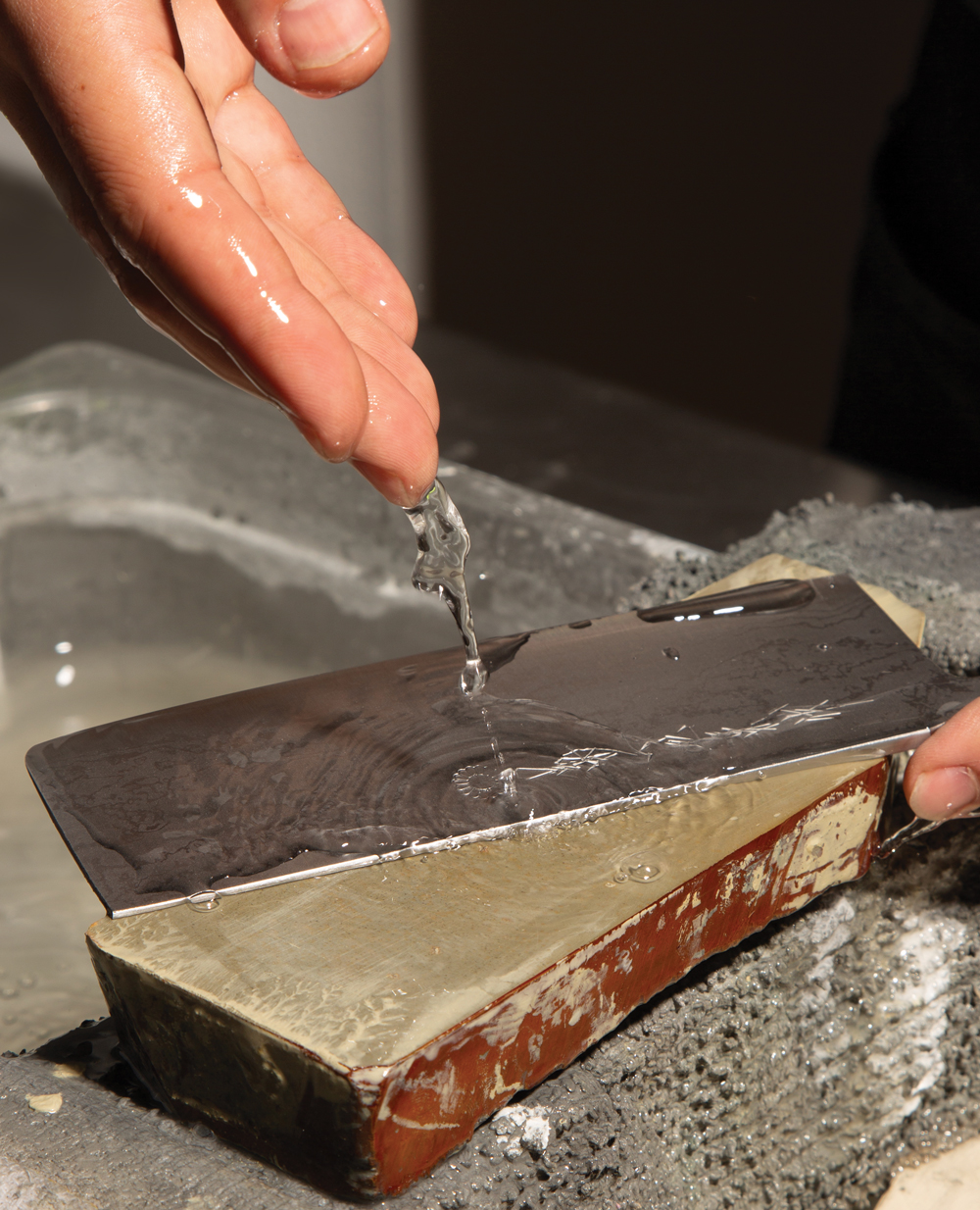 A knife-sharpening session begins with your tool of choice (a Japanese nakiri knife shown here) and a water-soaked whetstone and blade.