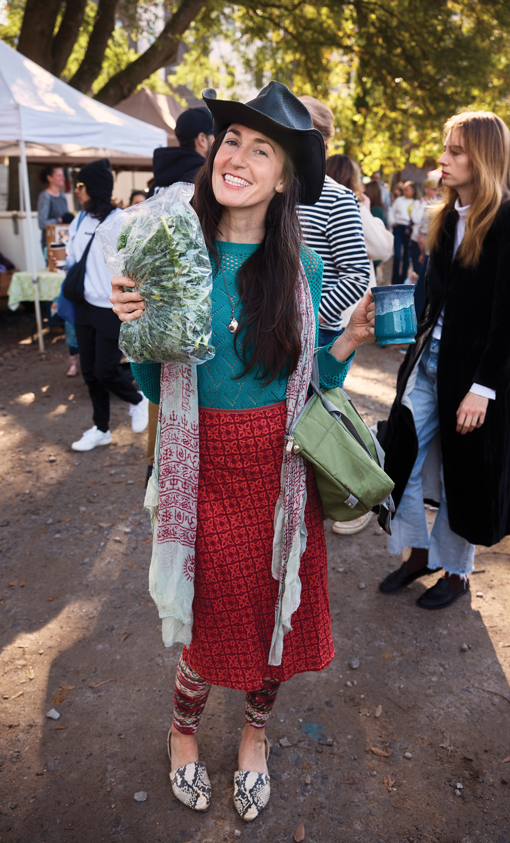 A woman holding a mug and vegetables at Grant Park Farmers Market