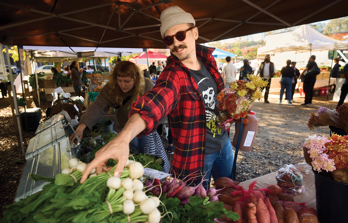 A man reaching for onions at the Grant Park Farmers Market