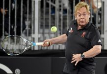 Elton John swinging a tennis racket
