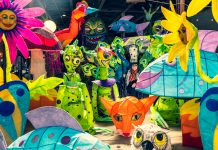 Chantelle Rytter in a warehouse surrounded by monster lanterns, flower lanterns, fish lanterns, and more—all of bright, vibrant colors