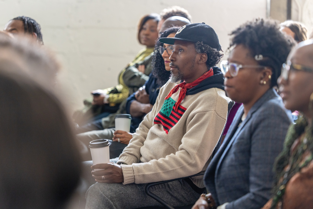 audience of the event sit, listening to the speakers