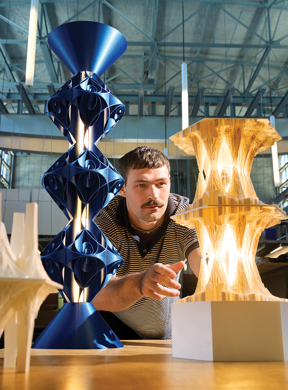 Sam Thurman stands between two of his intricate lighting fixtures