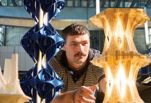 Sam Thurman stands between two of his intricate lighting fixtures