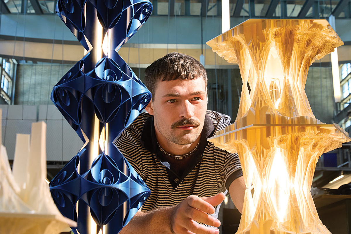 Sam Thurman stands between two of his intricate lighting fixtures