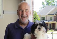 Michael Quattrochi smiles, holding a fluffy dog in his left arm