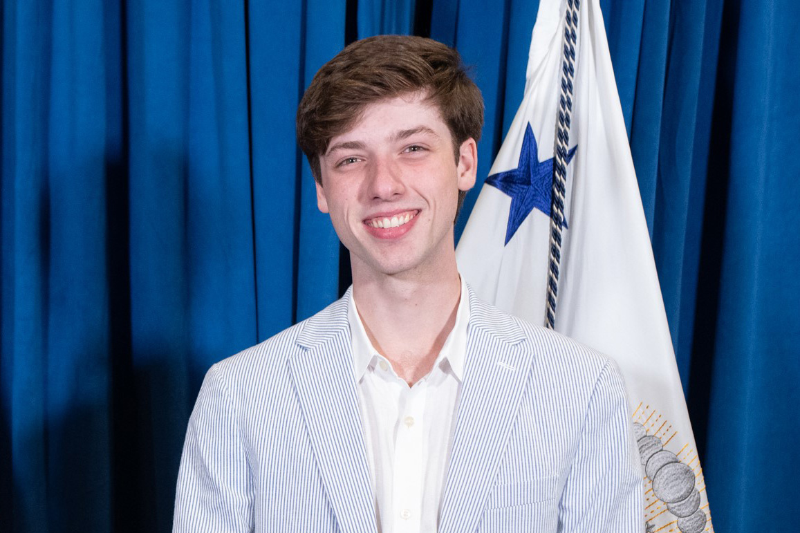 Parker Short smiling while wearing a blue pinstripe suit