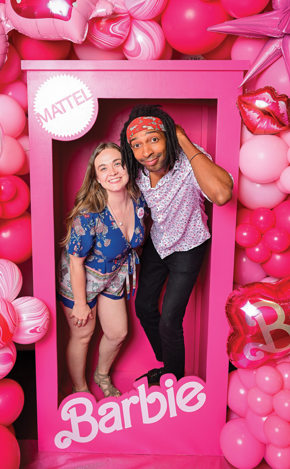 two movie attendees stand inside a life size barbie toy box