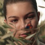 A close-up of Mila Harris's face in the film "Mary" while she looks at a butterfly on a branch