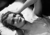 a woman lays in bed with her hand on her head