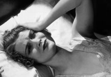 a woman lays in bed with her hand on her head