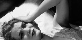 a woman lays in bed with her hand on her head