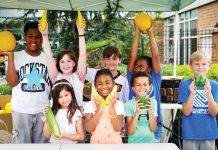 8 kids smile and pose while holding vegetables and helping their community