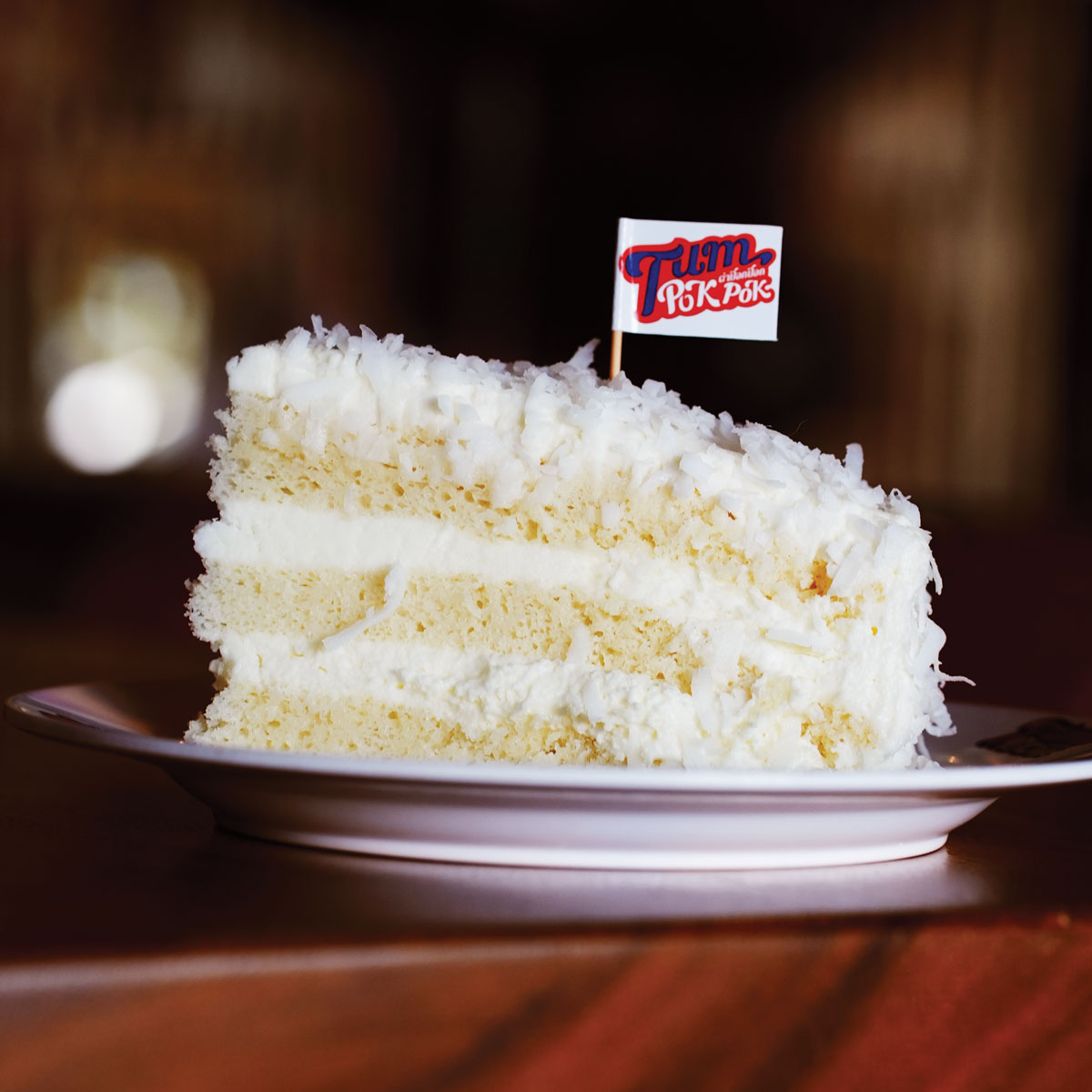 Coconut Cake on a plate with a small Tum Pok Pok flag