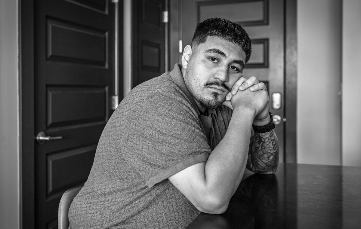 A black and white portrait of Vincent Leija leaning his head on his arms while sitting at a counter