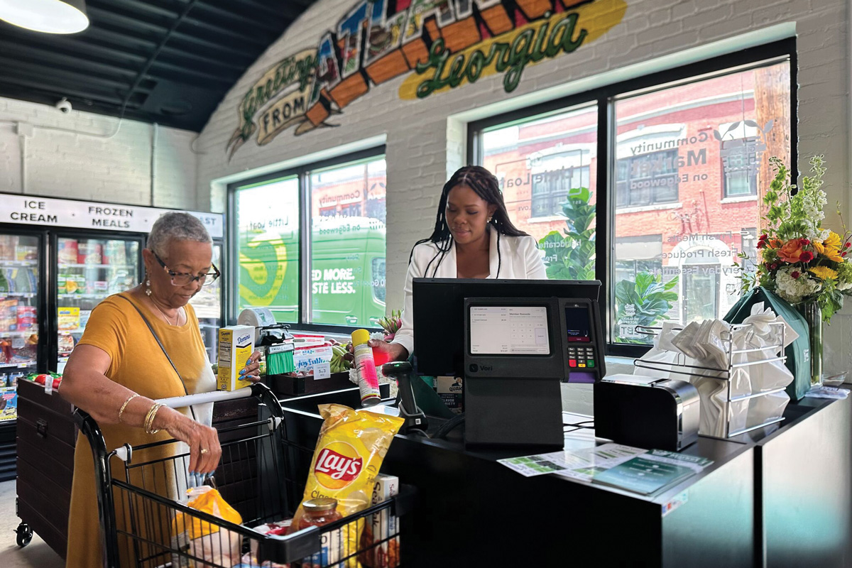 the inside of Goodr Community Market, at the cash register with a shopper buying affordable food