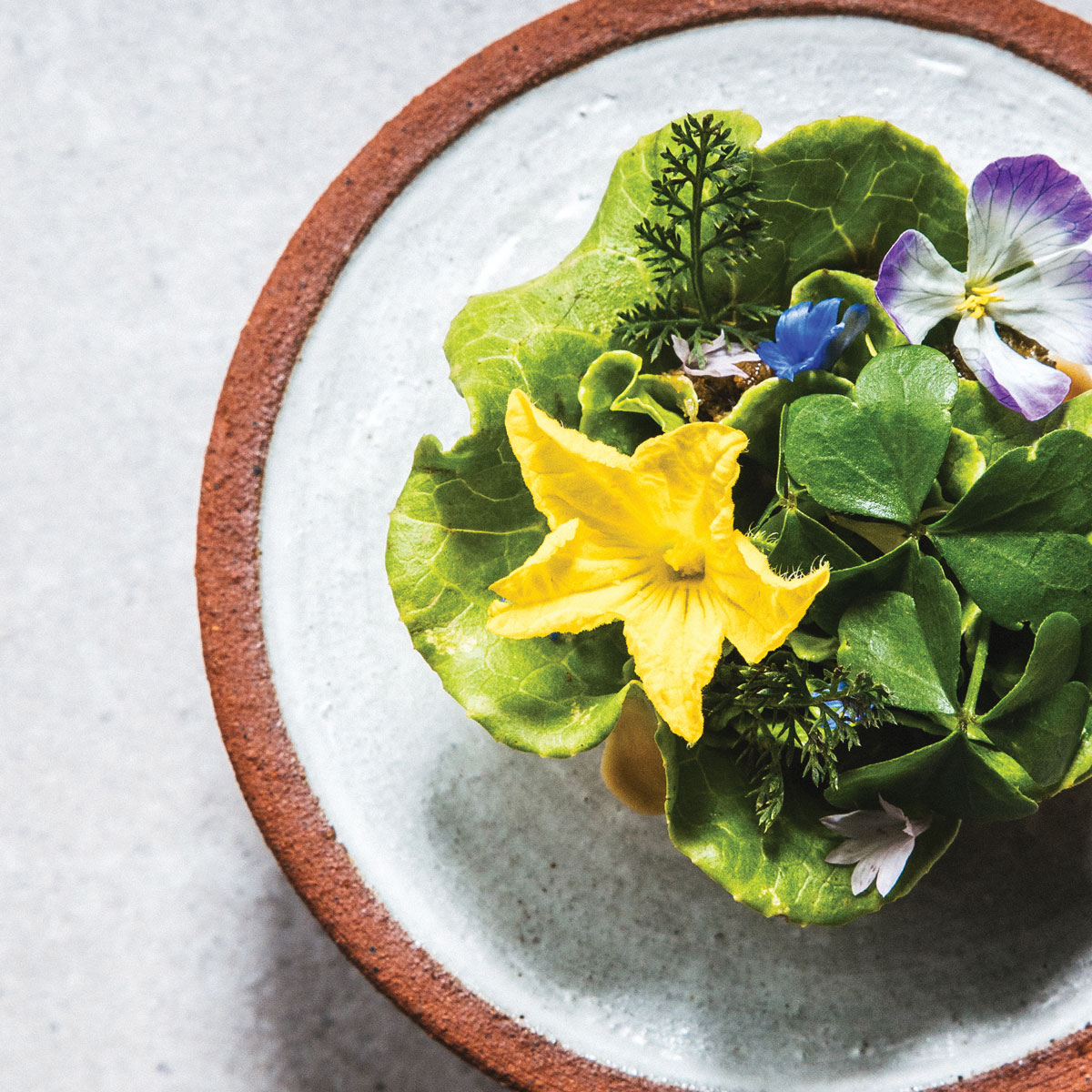A salad with purple and yellow flowers as garnish
