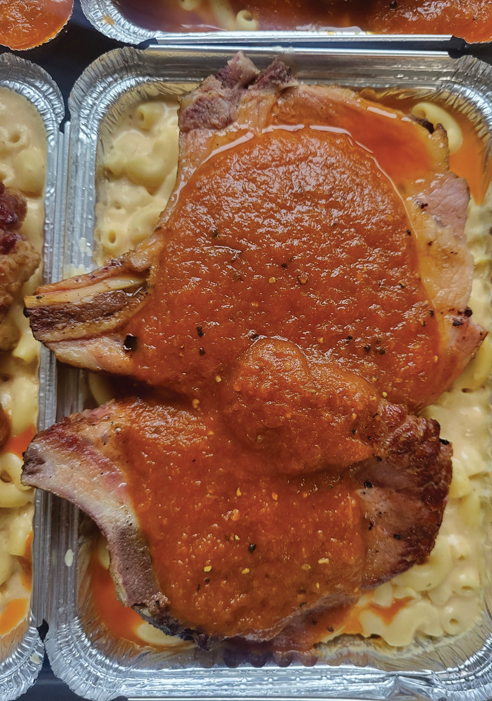 ribs on top of mac and cheese in aluminum platters from Casseroles Atlanta