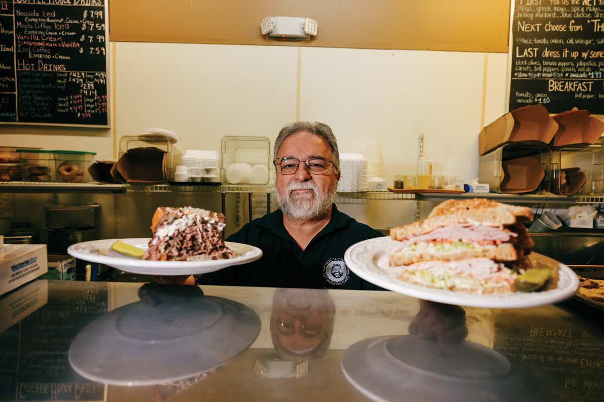 chef hold two sandwiches on a plate at Reuben’s Deli