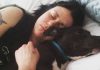 Katie Janness has her eyes closed as she lays in bed, hugging her dog, Bowie