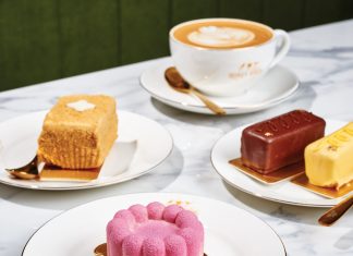 a latte cup and an assortment of pastries sit atop a white marble table at Honey Birds