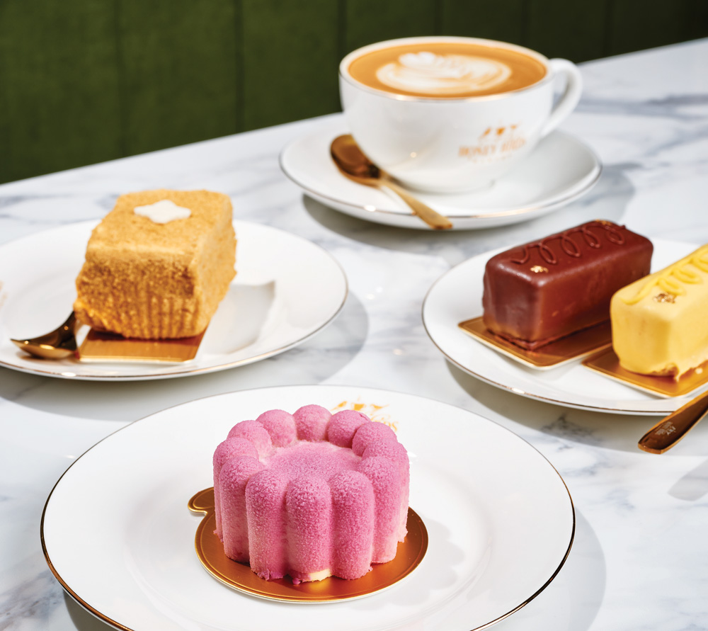 a latte cup and an assortment of pastries sit atop a white marble table at Honey Birds