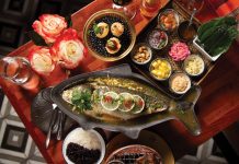 A spread of the whole branzino and the colorful components, including wrapping leaves of miang kham